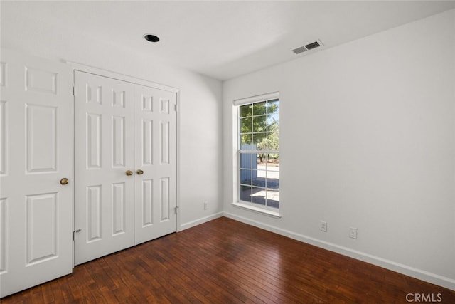 unfurnished bedroom with dark hardwood / wood-style floors and a closet