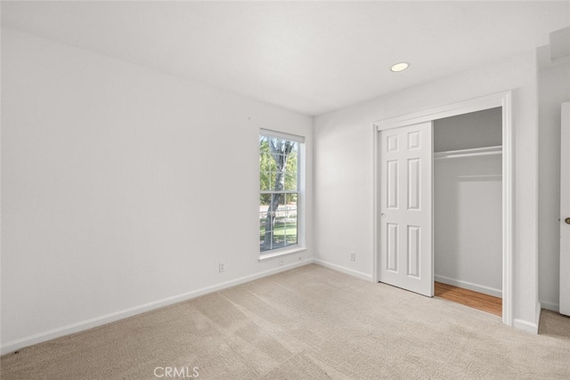 unfurnished bedroom with light carpet and a closet