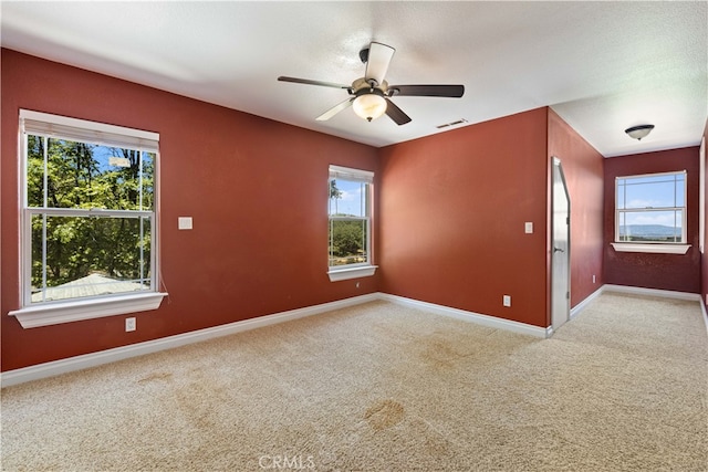 carpeted empty room with ceiling fan and a wealth of natural light