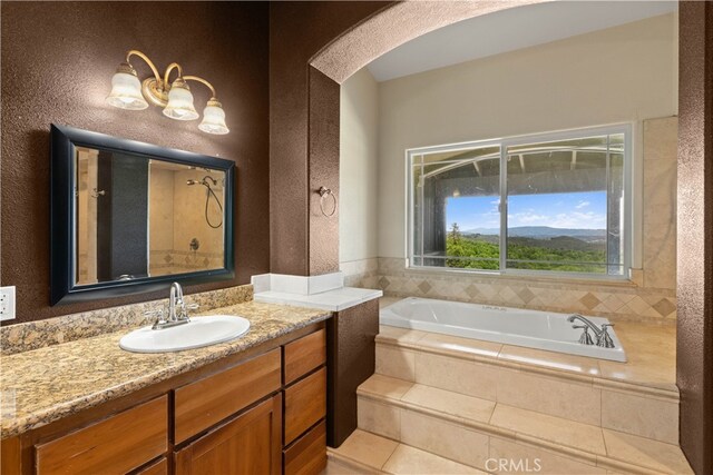 bathroom with tiled tub and vanity