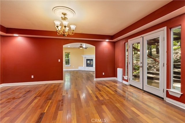 empty room with ceiling fan with notable chandelier and hardwood / wood-style flooring