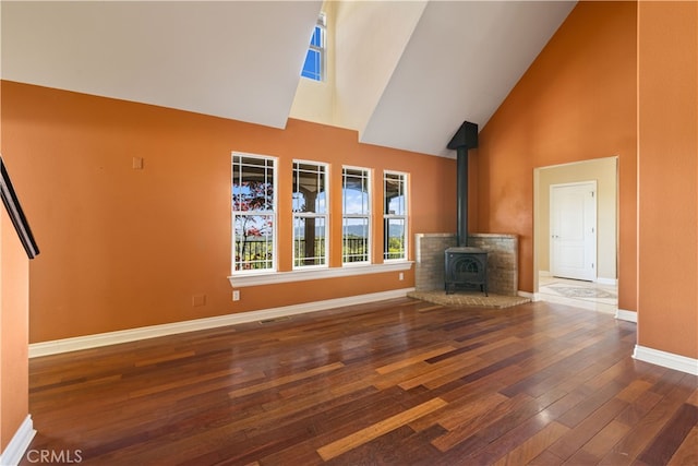 unfurnished living room with high vaulted ceiling, a wood stove, and dark wood-type flooring