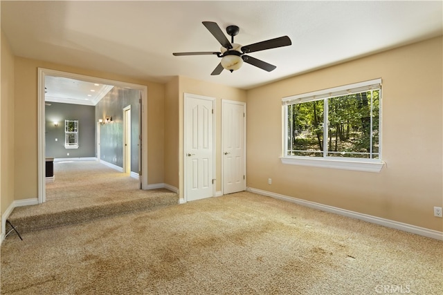 unfurnished bedroom with ceiling fan, two closets, crown molding, and light carpet