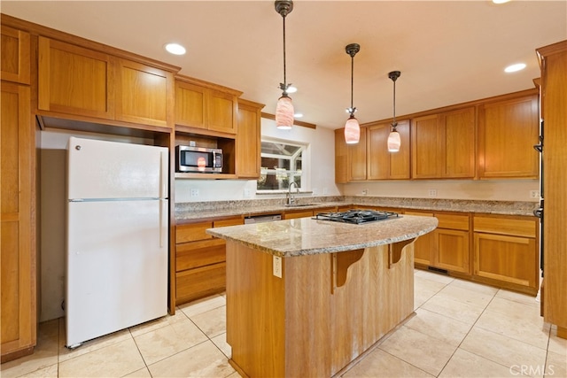 kitchen with pendant lighting, light stone counters, sink, a kitchen island, and stainless steel appliances