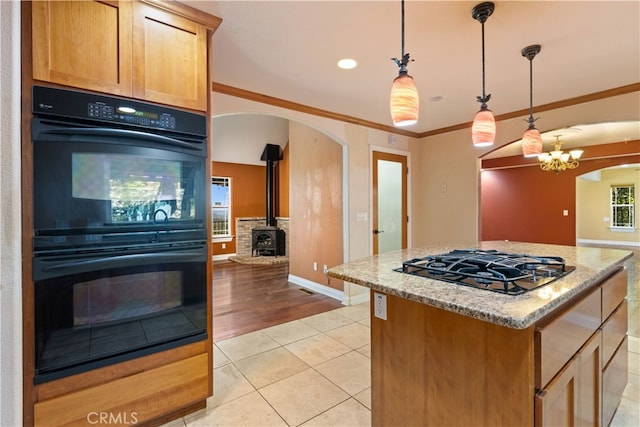 kitchen with light hardwood / wood-style floors, a wood stove, an inviting chandelier, decorative light fixtures, and double oven