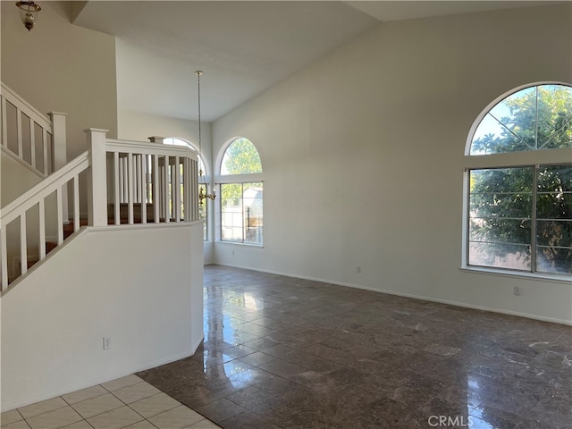 empty room featuring a chandelier and high vaulted ceiling