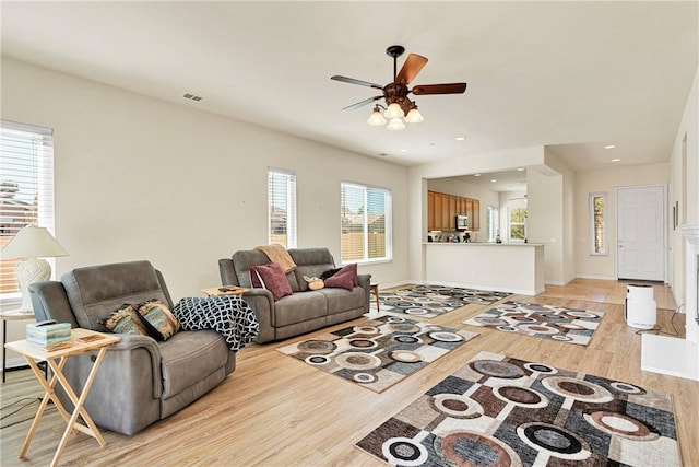 living room with light hardwood / wood-style flooring, a wealth of natural light, and ceiling fan