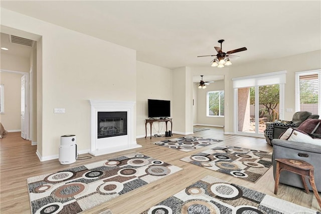 living room with light hardwood / wood-style floors, a wealth of natural light, and ceiling fan