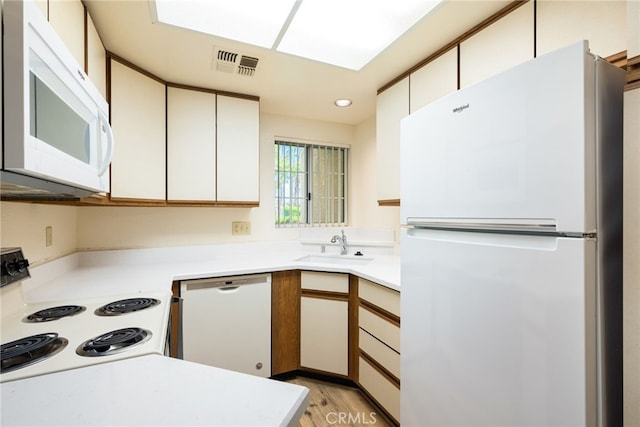 kitchen with white appliances, light hardwood / wood-style floors, white cabinetry, and sink