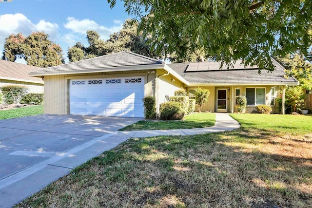 ranch-style house featuring a garage, solar panels, and a front lawn