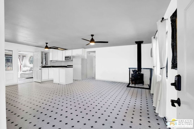 living room featuring sink, ceiling fan, and a wood stove