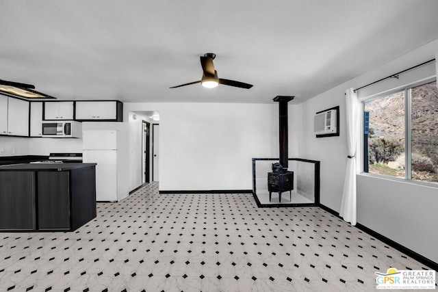 kitchen featuring white fridge, range, a wood stove, white cabinets, and ceiling fan