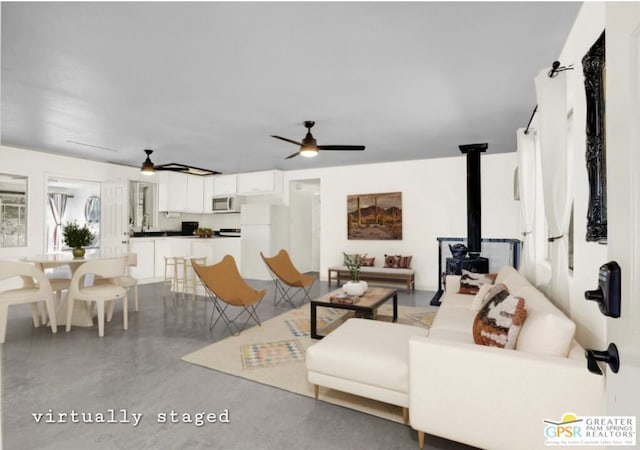 living room with ceiling fan and a wood stove