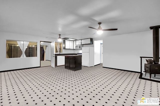 kitchen featuring white refrigerator, a kitchen island, ceiling fan, and a wood stove