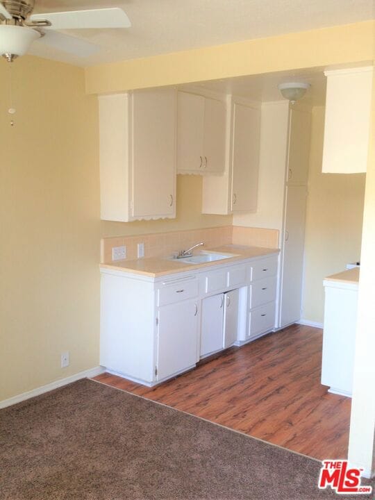 kitchen with ceiling fan, white cabinetry, sink, and dark wood-type flooring