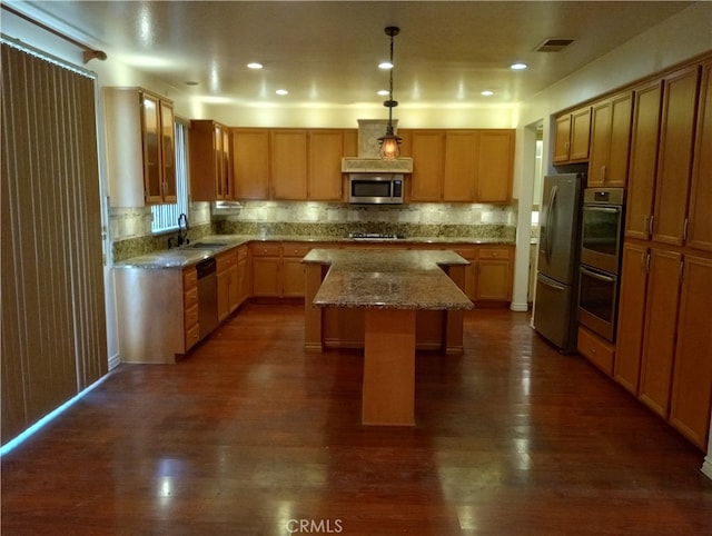 kitchen with pendant lighting, sink, a kitchen island, stainless steel appliances, and dark hardwood / wood-style flooring