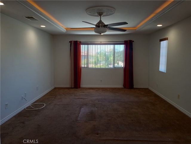 carpeted spare room with a tray ceiling and ceiling fan