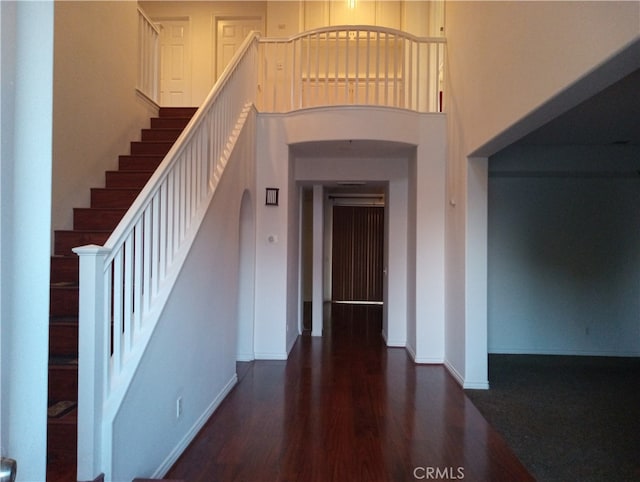 stairway featuring wood-type flooring and a high ceiling