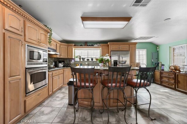 kitchen featuring stainless steel appliances, visible vents, a kitchen island, and a breakfast bar area