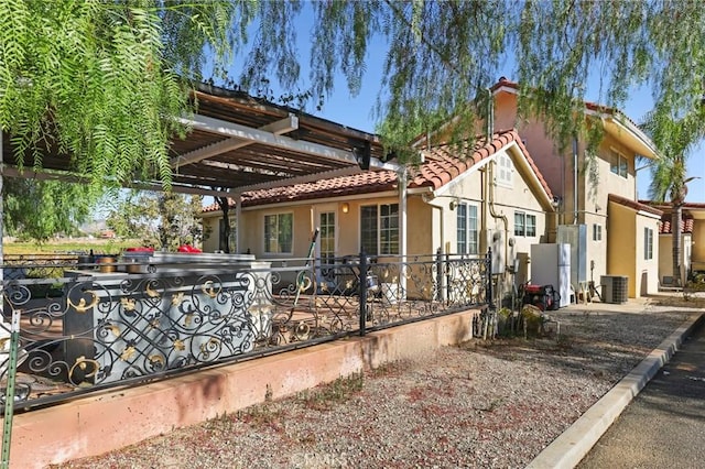 exterior space with a tiled roof, central air condition unit, stucco siding, and a pergola