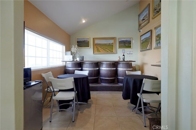 dining room featuring vaulted ceiling, a bar, and tile patterned floors