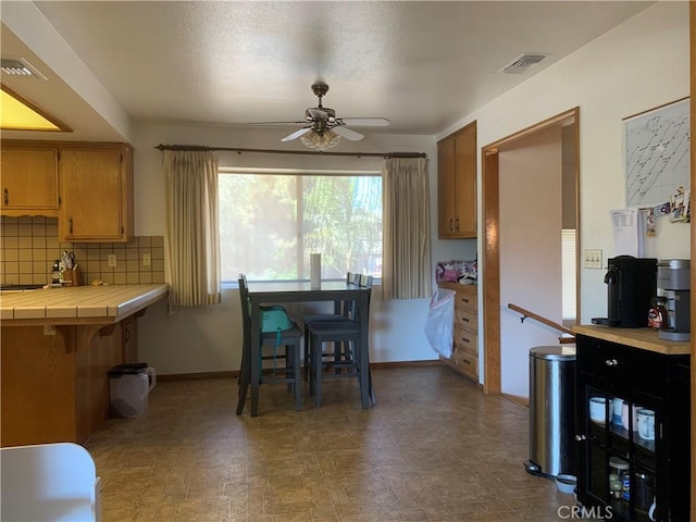 kitchen featuring backsplash, tile countertops, and ceiling fan