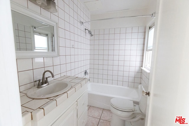 full bathroom with vanity, tile patterned flooring, tiled shower / bath combo, decorative backsplash, and tile walls