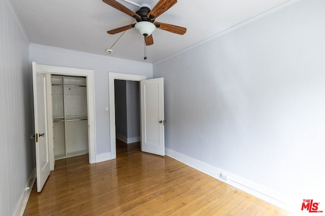 unfurnished bedroom with hardwood / wood-style flooring, ceiling fan, crown molding, and a closet