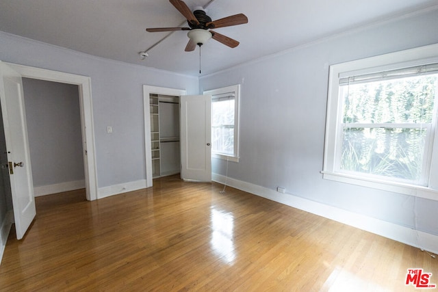 unfurnished bedroom with ceiling fan, wood-type flooring, crown molding, and a closet