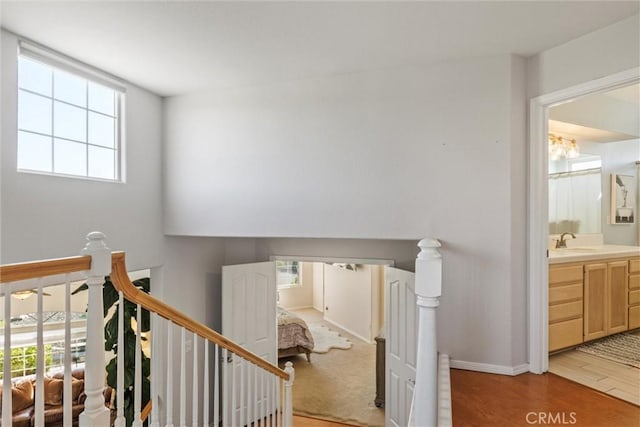 stairway with plenty of natural light, wood-type flooring, and sink