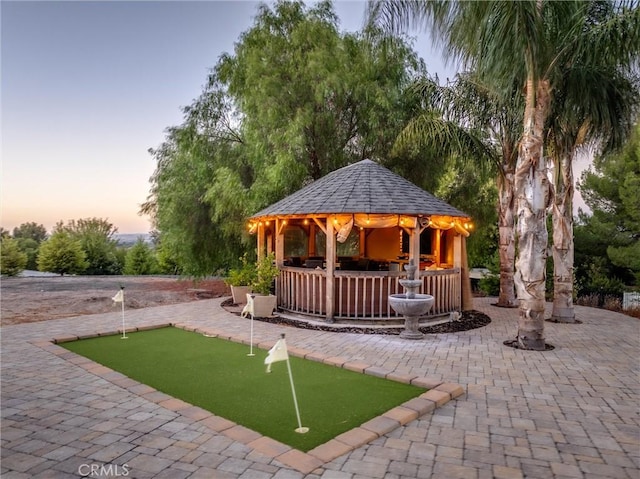 playground at dusk featuring a gazebo and a patio area