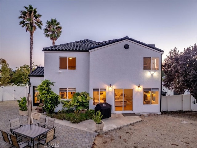 back house at dusk with a patio area