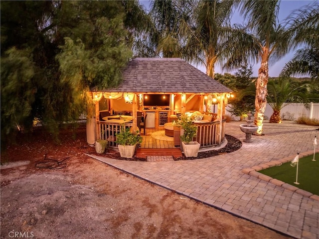 patio terrace at dusk with a wooden deck and an outdoor kitchen