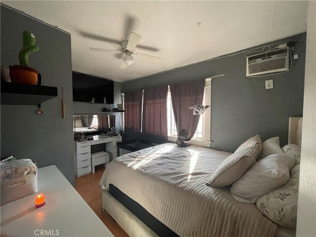 bedroom with a wall mounted air conditioner, wood-type flooring, and ceiling fan