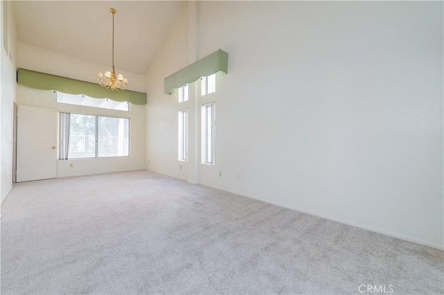 carpeted spare room featuring high vaulted ceiling and a chandelier