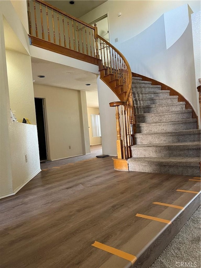 staircase featuring wood-type flooring and a high ceiling