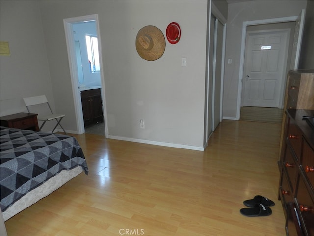 bedroom with light hardwood / wood-style floors and ensuite bathroom