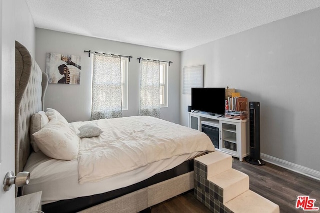 bedroom with a textured ceiling and dark hardwood / wood-style flooring