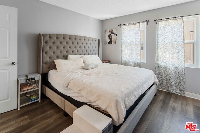 bedroom with multiple windows and dark hardwood / wood-style floors