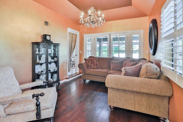 living room featuring a tray ceiling, dark hardwood / wood-style floors, and an inviting chandelier