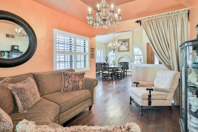 living room featuring dark hardwood / wood-style flooring, a chandelier, and vaulted ceiling