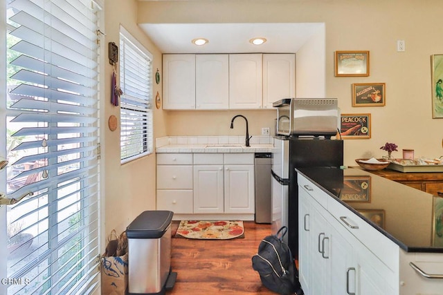 kitchen featuring sink, white cabinetry, dark wood-type flooring, and stainless steel refrigerator