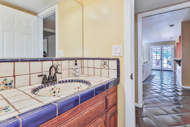 bathroom with backsplash, french doors, and vanity