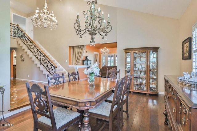 dining space featuring wood-type flooring, a towering ceiling, and french doors