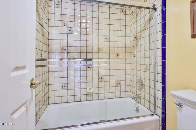 bathroom featuring toilet and combined bath / shower with glass door