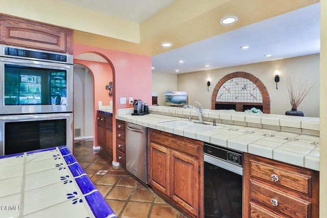 kitchen with tile countertops, sink, and stainless steel appliances