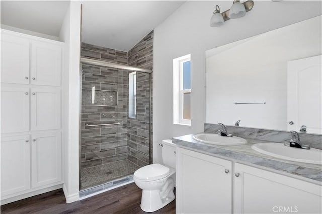 bathroom with hardwood / wood-style floors, vaulted ceiling, toilet, vanity, and a shower with shower door