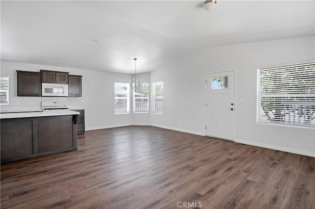 kitchen with dark wood-type flooring, decorative light fixtures, vaulted ceiling, dark brown cabinets, and range