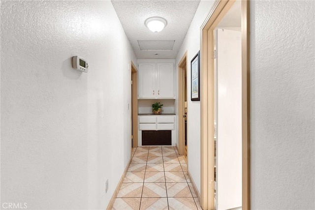 corridor featuring a textured ceiling and light tile patterned floors