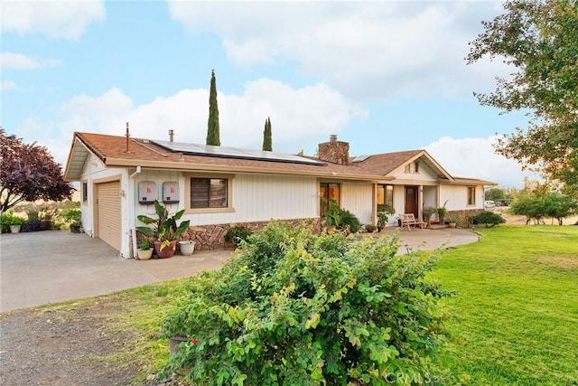 ranch-style house featuring a garage, a front lawn, solar panels, and a patio